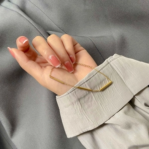 Close-up of minimalist gold chain bracelet featuring three sleek cylindrical metal tube charms