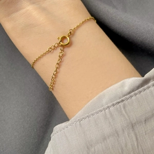 Detail of minimalist gold tube chain bracelet with spring ring clasp on woman's wrist