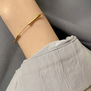Minimalist gold cylindrical tube chain bracelet shown on a female wrist in style