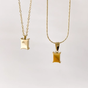 Detail of minimalist gold necklaces featuring o-chain and snake chain with square pendants