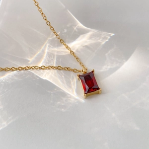 Detail of red emerald-cut crystal pendant on a gold necklace with sparkling light effects