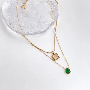 Détail du collier double rang en or avec fermoir gravé K18 et pendentif goutte vert
