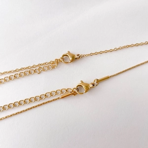 Detail of gold lobster clasp and adjustable extension chain on two layered necklaces