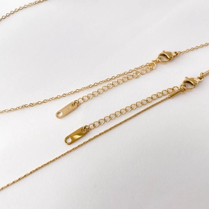 Detailed close-up of a gold lobster clasp and K18 engraved tag on a dainty necklace