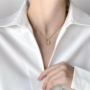 Collier doré minimaliste avec pendentif carré ambré porté sur chemise