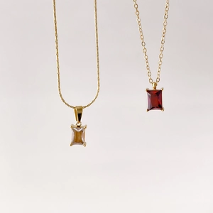Detail of square-cut red and clear gemstone pendants with gold claw settings