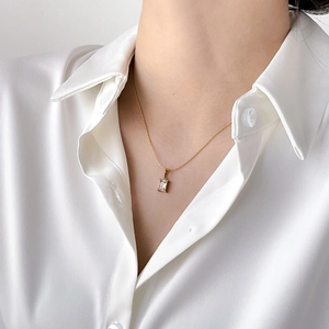Close-up of a French style gold chain necklace with a square clear crystal pendant