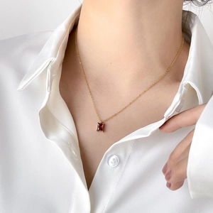 French style minimalist gold necklace with rectangular red gemstone on a silk background