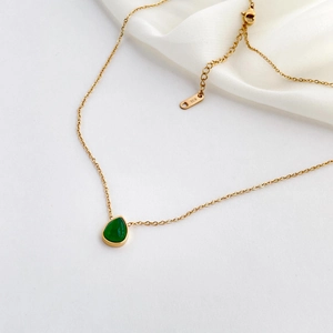 Détail du poinçon K18 sur le fermoir d'un collier goutte d'eau verte avec chaîne dorée