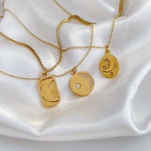 Elegant gold crescent moon and star pendant necklaces with pavé zircon on white silk background