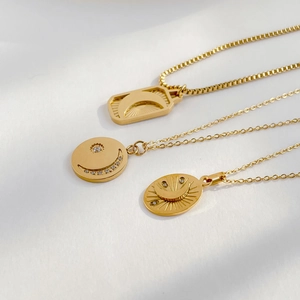 Detailed view of three gold moon and sun pendants with sparkling zircon on high-quality chains