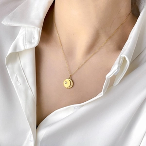 Close-up of gold moon and star pendant necklace on model wearing white silk shirt