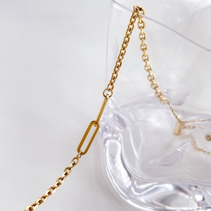 Detail einer minimalistischen Goldkette mit ovalem Glied auf strukturiertem Glas