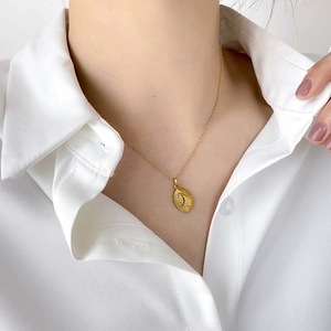 Elegant gold oval moon and sun pendant necklace with cubic zirconia on white shirt