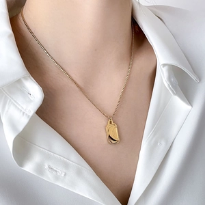 Detailed close-up of a golden moon necklace pendant on a minimalist white shirt