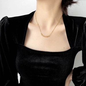 Close-up of golden necklace with five twisted beads on a model wearing black velvet