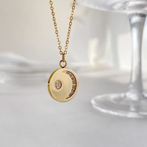 Macro shot of gold disc pendant necklace with sparkling diamond crescent moon and star