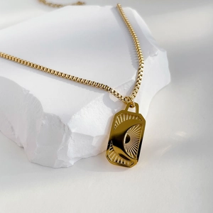 Detailed close-up of 18K gold crescent moon and sunburst engraved rectangular pendant