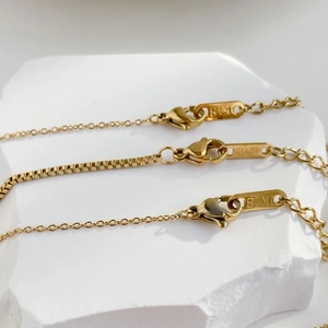 Detailed close-up of gold box chains with lobster clasps and K18 hallmark on stone
