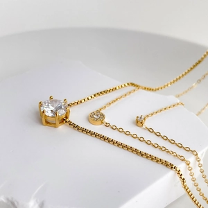 Detailed view of three minimalist gold necklaces with sparkling cubic zirconia pendants