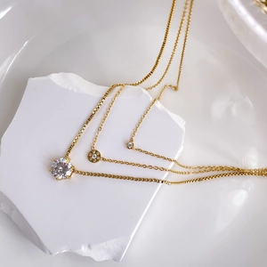 Detailed view of layered gold necklaces with zircon pendants and box chain styling