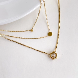 Detail view of gold layered necklace set with hexagonal crystal and round charms
