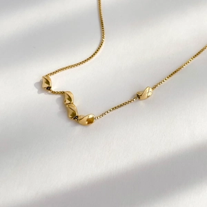 Detail of gold box chain necklace featuring five irregular organic metal bead charms