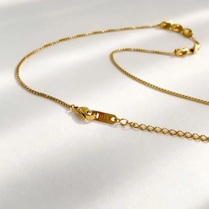 Close-up of K18 hallmark on golden necklace with lobster clasp and box chain detail