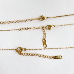 Detailed macro view of 18K gold plated box and link chains with lobster clasp and K18 stamp