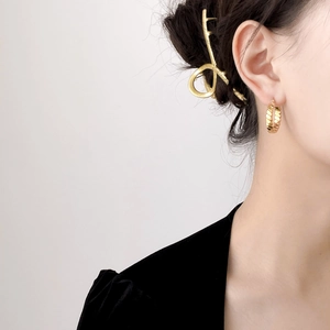 Minimalist gold twisted hoop earrings and fluid claw clip worn by model in profile view