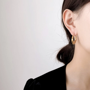 Close-up of golden minimalist twisted hoop earrings worn for a sleek modern aesthetic