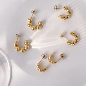 Detailed view of three-piece gold twisted hoop and beaded metal earring set