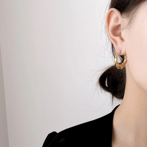 Minimalist twisted gold hoop earrings for women with polished spiral design shown on model
