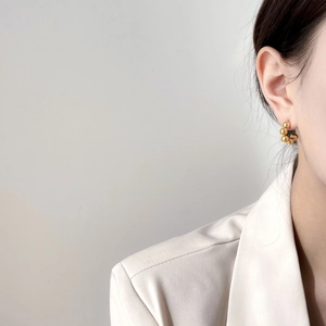 Elegant gold beaded hoop earrings shown on a model wearing a white blazer