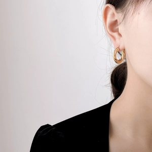 Polished gold twisted hoop earring worn by a model in a minimalist stylish close-up