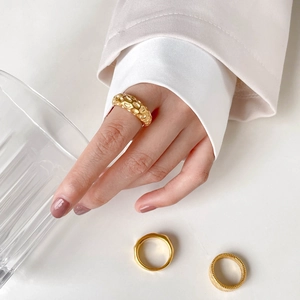 Close-up of French vintage gold rings with hammered texture and braided embossed details