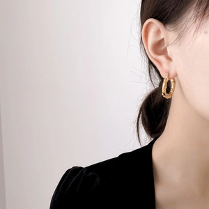 Close-up of golden twist hoop earrings showing spiral texture and earlobe fit
