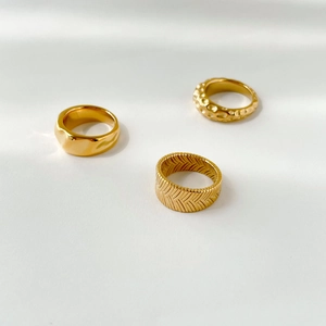 Macro detail of three gold rings showing smooth, hammered, and woven textures