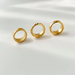 Detailed view of three gold textured rings featuring wheat and hammered patterns