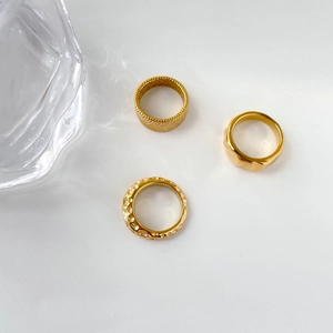 Detailed close-up of three gold rings with wheat pattern and hammered metal texture