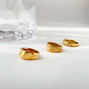 Close-up of three gold textured rings with woven and crater patterns on white background