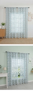 Close-up of light blue sheer curtains with white floral embroidery in a modern room