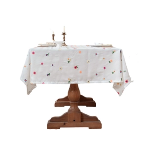 Thickened white tablecloth with colorful floral embroidery on a dark wood table