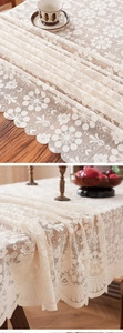 Close-up of elegant cream floral lace tablecloth with scalloped edges on a wooden table