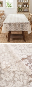 Close-up of cream white floral lace tablecloth showing intricate mesh and wavy hollow edges