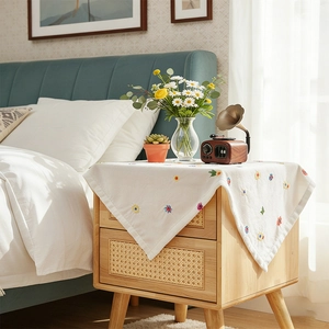 White chiffon dust cover with floral embroidery on wooden bedside table in bedroom