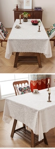 Detailed view of cream lace tablecloth featuring floral paisley patterns and scalloped edges