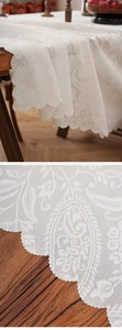 Detail of white paisley lace tablecloth with scalloped edges and floral mesh texture