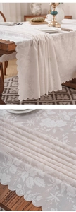Detail of off-white lace tablecloth featuring rose floral patterns and scalloped edges