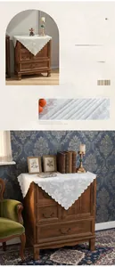 Detail of white floral lace cover cloth featuring vintage scalloped edges on wood dresser